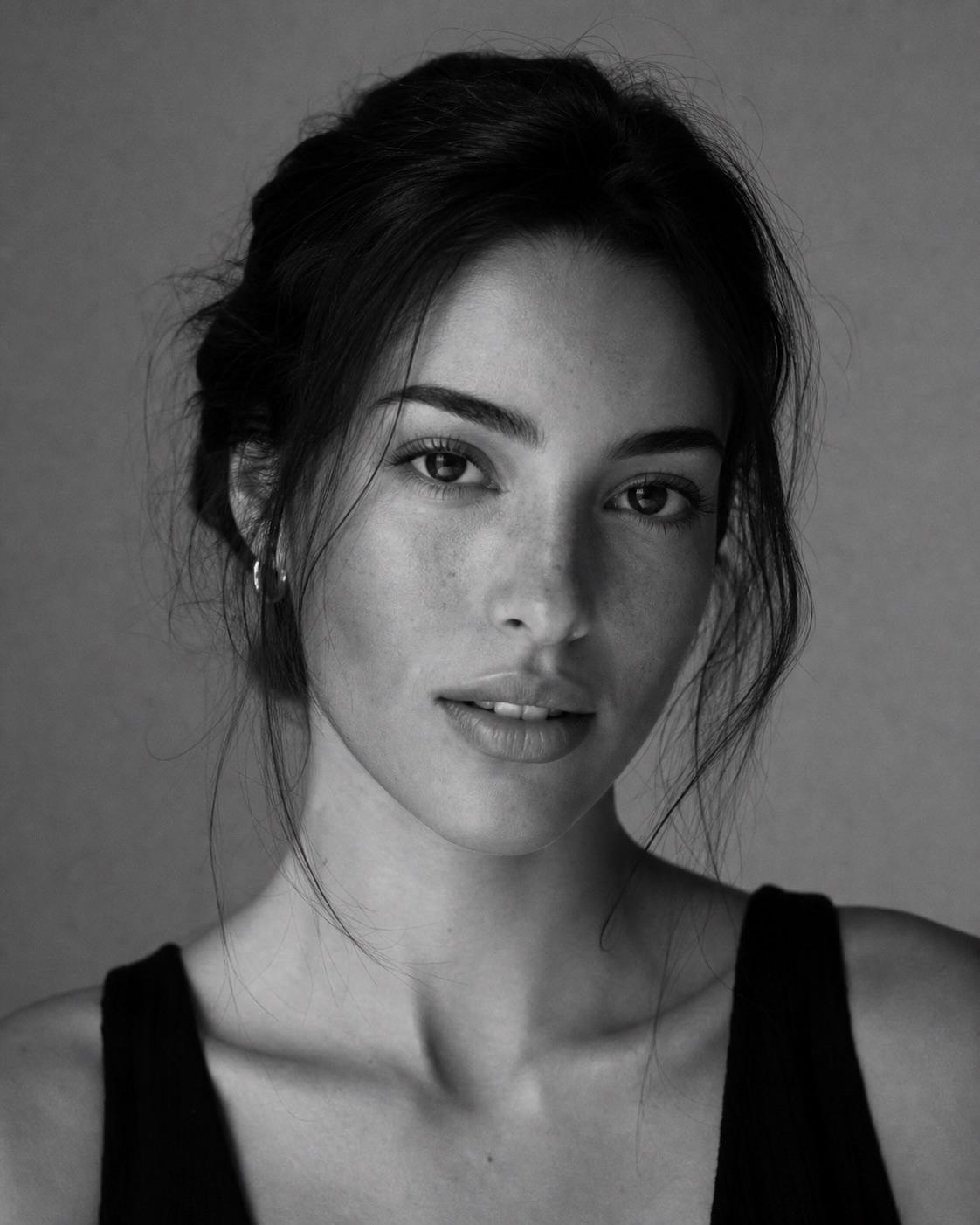 Entirely synthetic adult studio portrait with a restrained black-and-white tonal grade