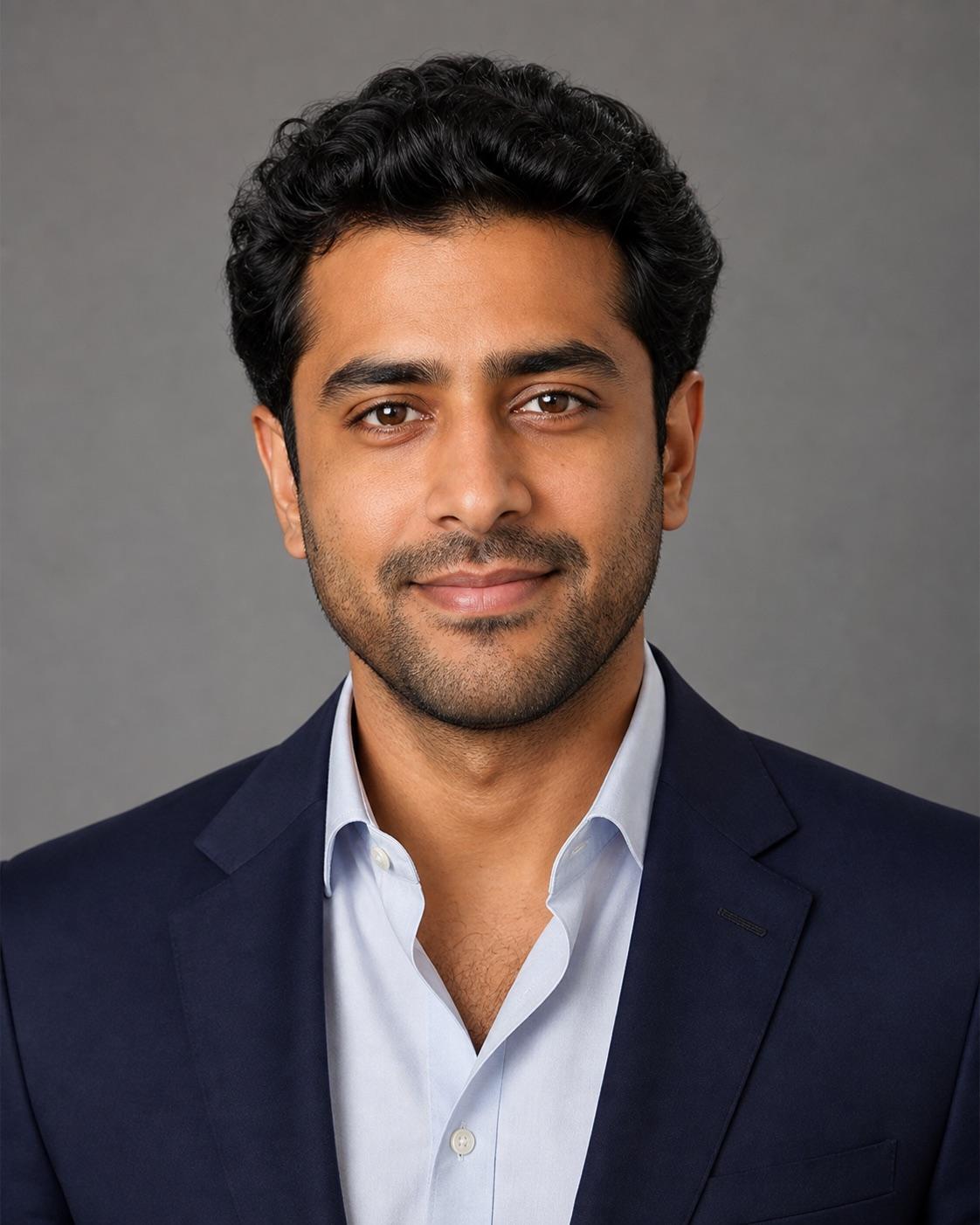 Entirely synthetic adult man in a navy blazer against a clean warm-gray studio background